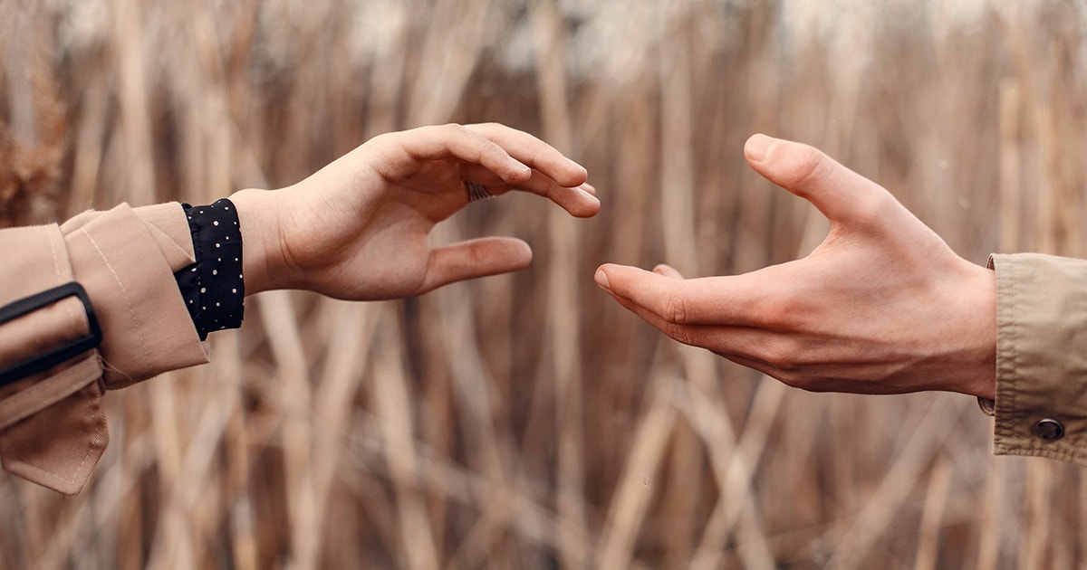 Egy nő és egy férfi egymás felé nyújtja a kezét, de nem érik el egymást
